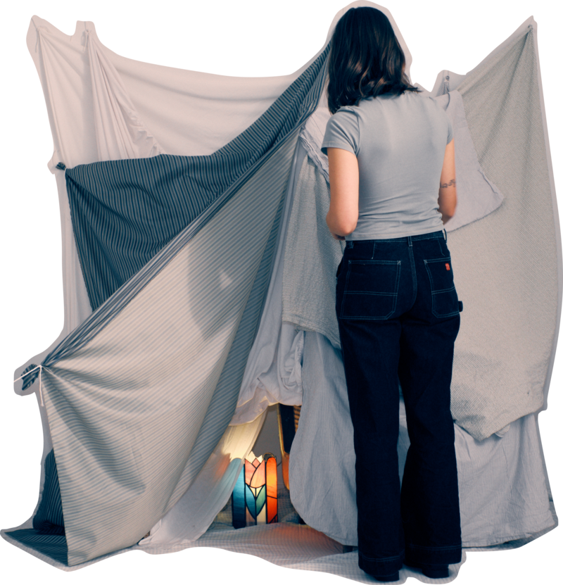 Lea is standing
	  in front of a blanket fort with her back toward us. Inside the fort, a lit
		stained-glass lamp can bee seen. The lamp creates interesting shadows over
		the blanket fort.